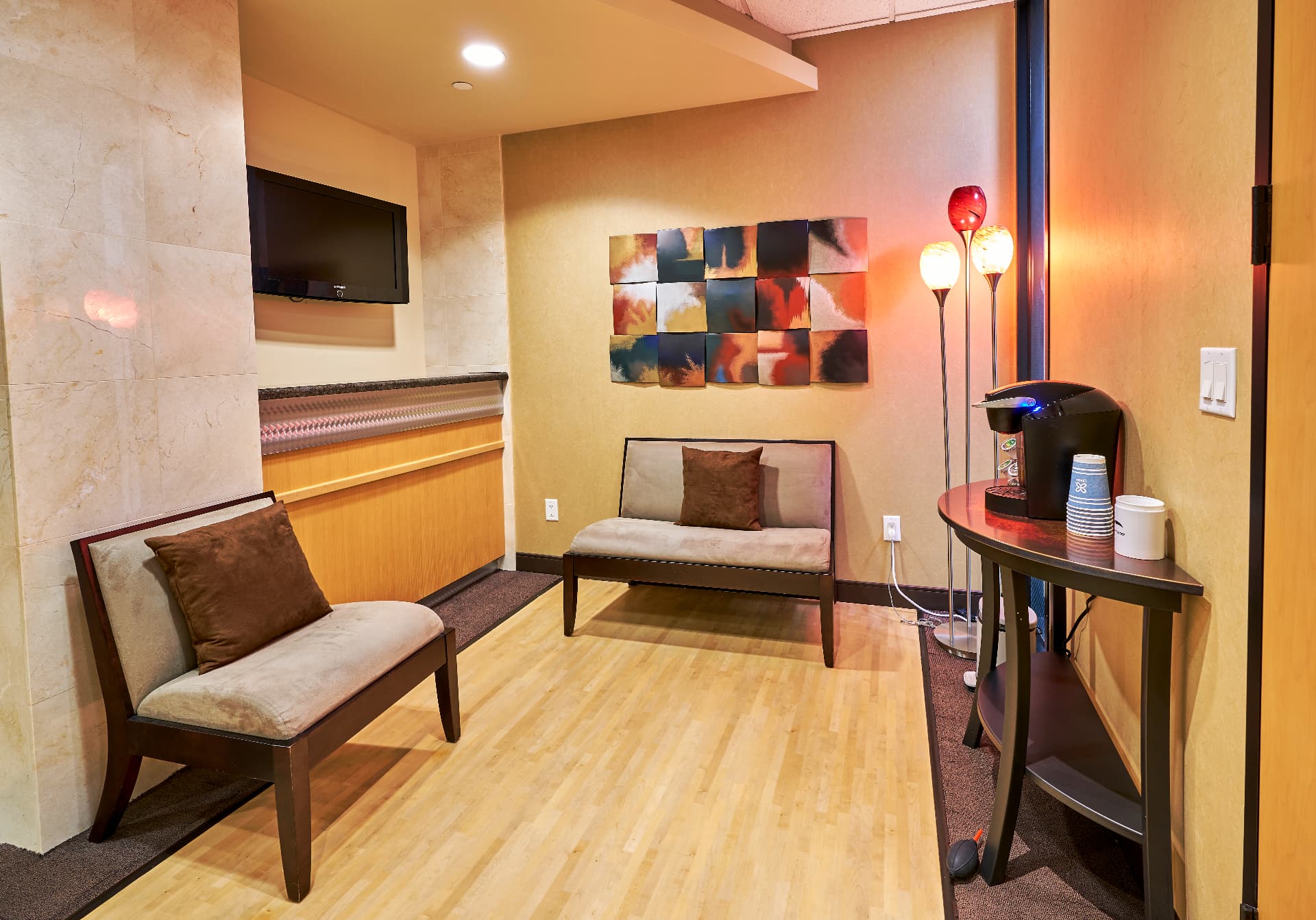 Quiet waiting nook at Uptown Dentistry with cushioned seating, artwork and a coffee station